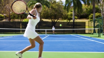 two people playing tennis in a tropical setting