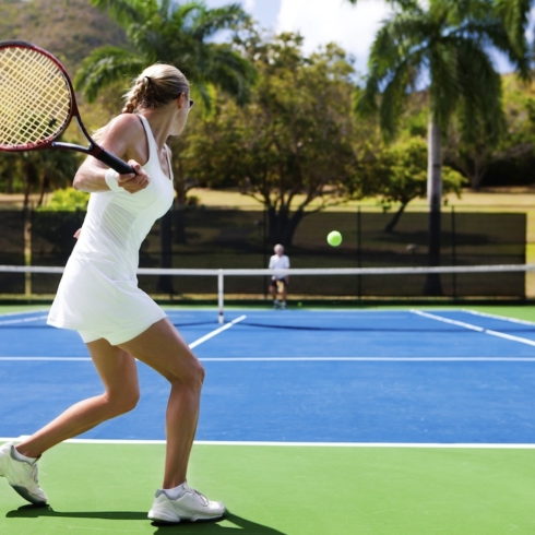 two people playing tennis in a tropical setting